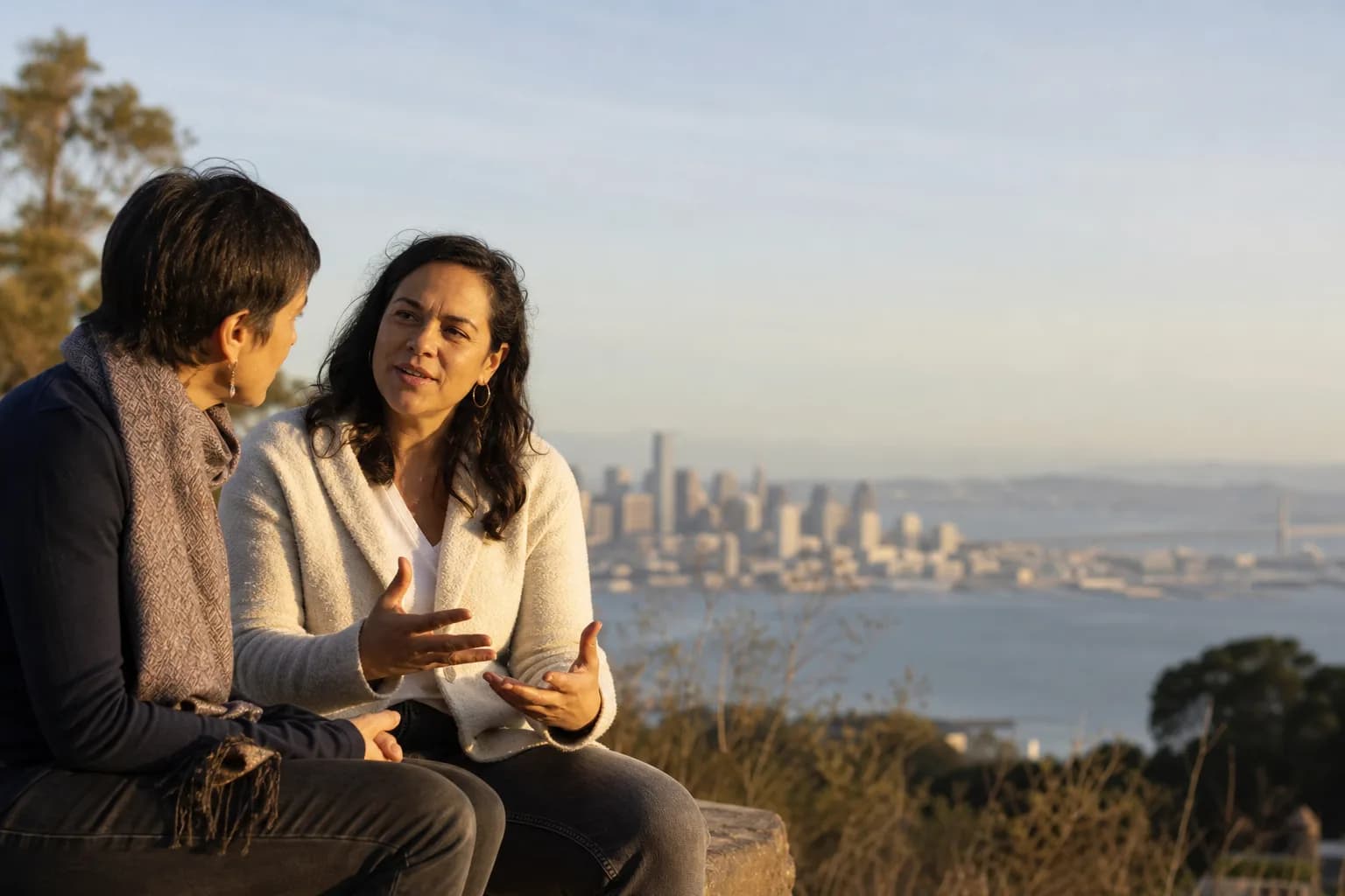 Two women in an unhurried conversation on a hillside above the San Francisco bay