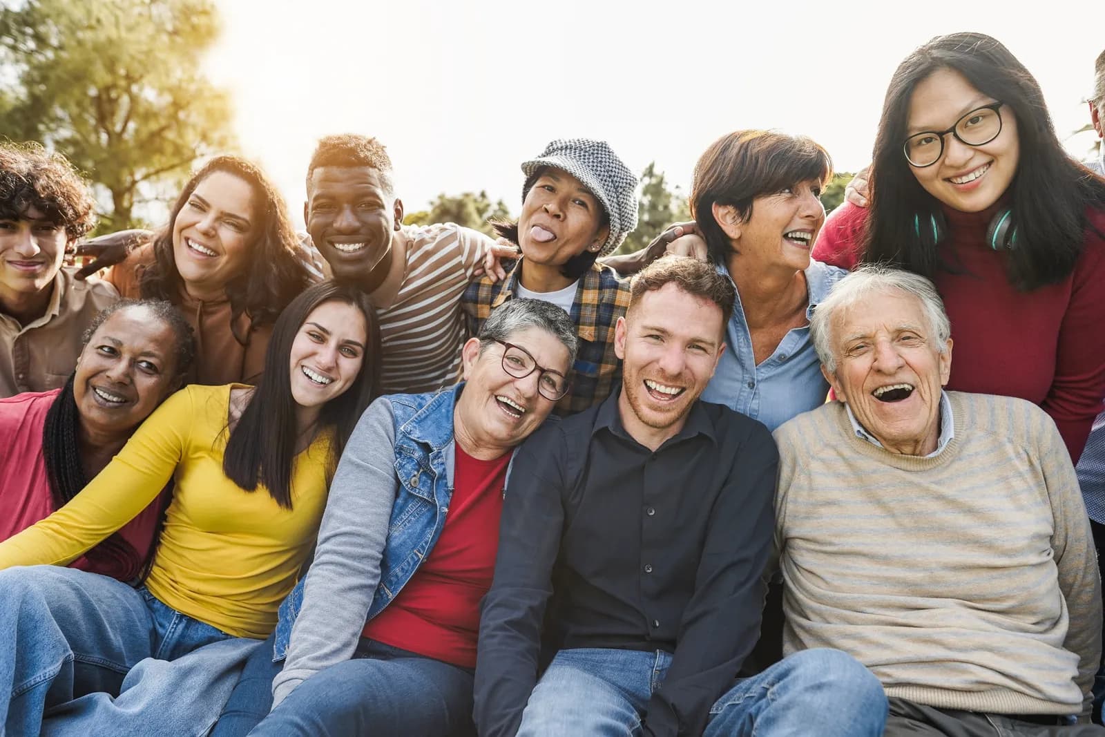 A diverse, multigenerational group of people smiling together outdoors