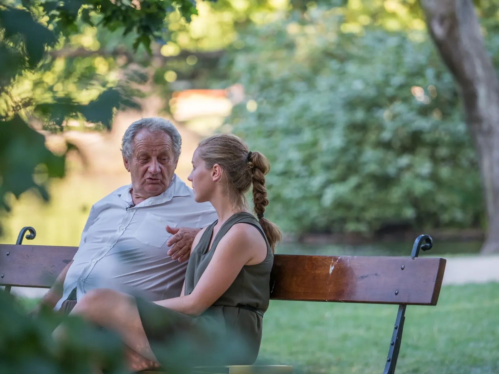 Two people sitting on a bench, listening to one another, intent on hearing each other